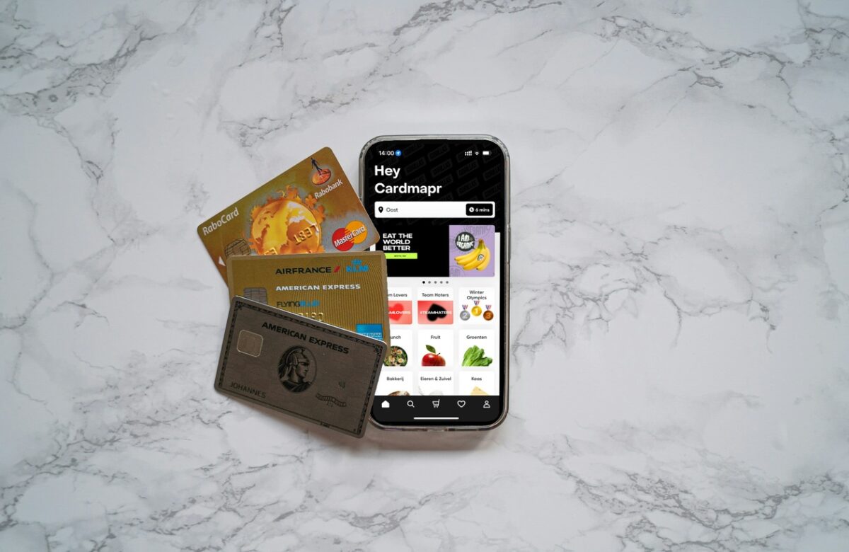 Various beginner travel credit cards including American Express and Air France cards displayed alongside a smartphone showing a payment app on marble surface