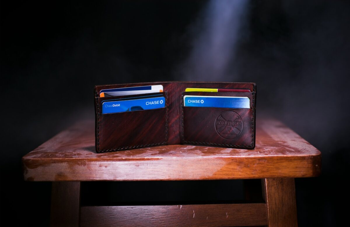 Multiple airline credit cards displayed in an open leather wallet on a wooden stool