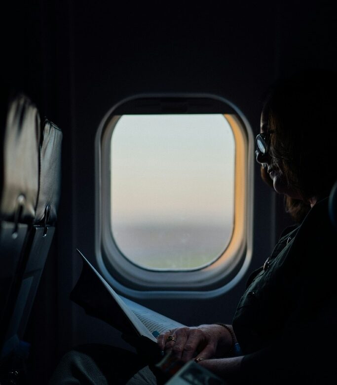 Silhouette of traveler sitting by airplane window with travel credit card rewards