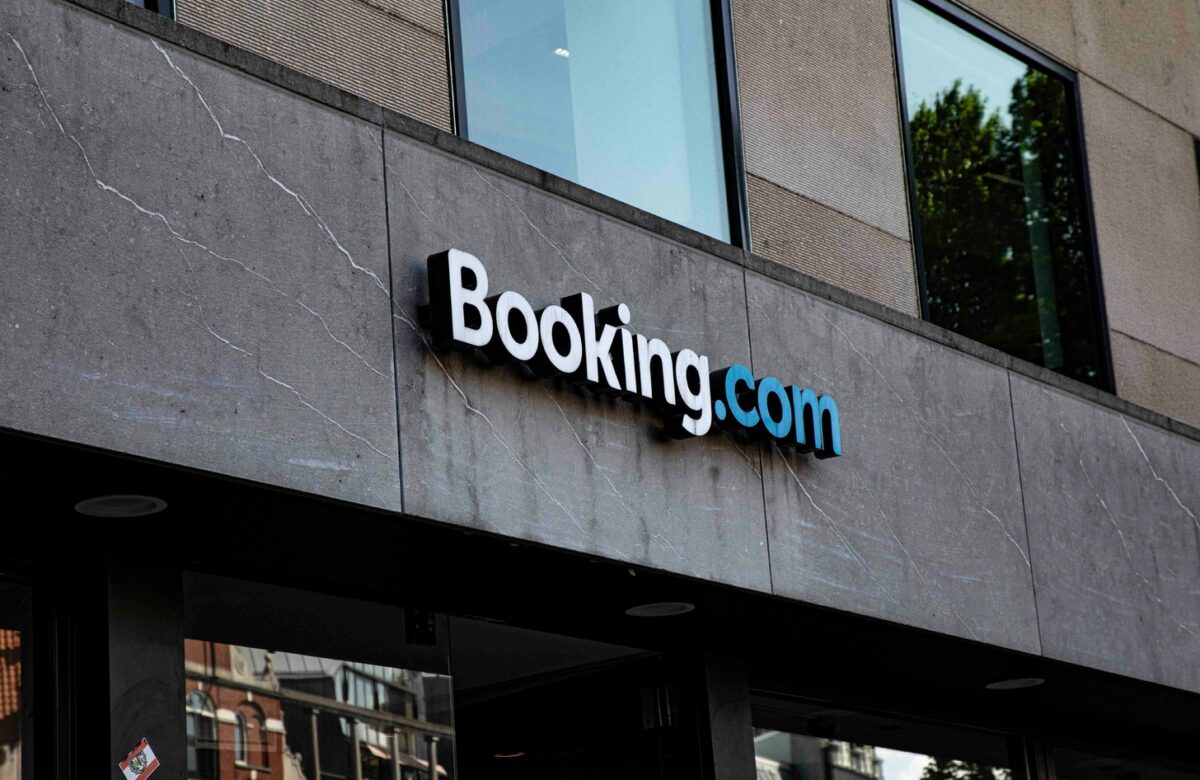 Booking.com logo mounted on gray concrete building facade referencing travel booking sites guide